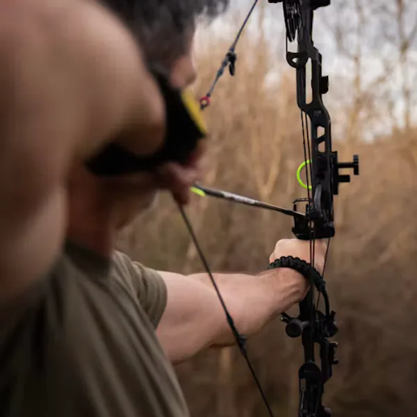 Archer at full draw with a compound bow in a field