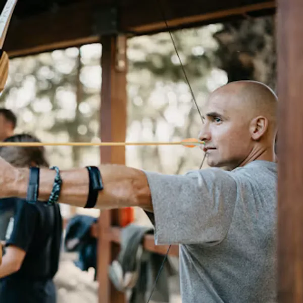 Archer at full draw with a recurve on an outdoor range